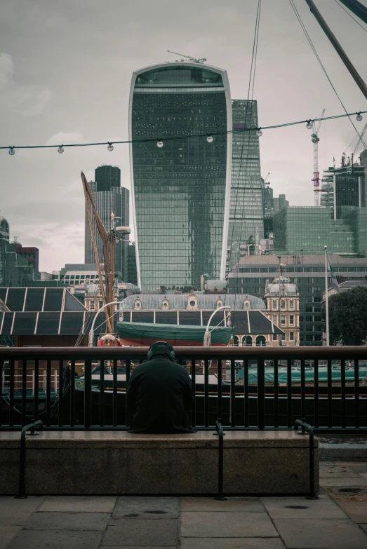 a man sitting on top of a bench in front of some tall buildings