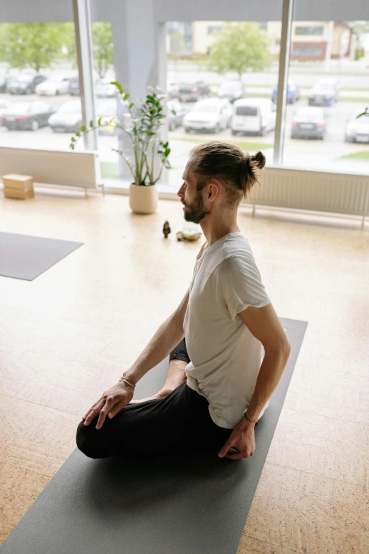 a man sitting on a yoga mat looking out of the window