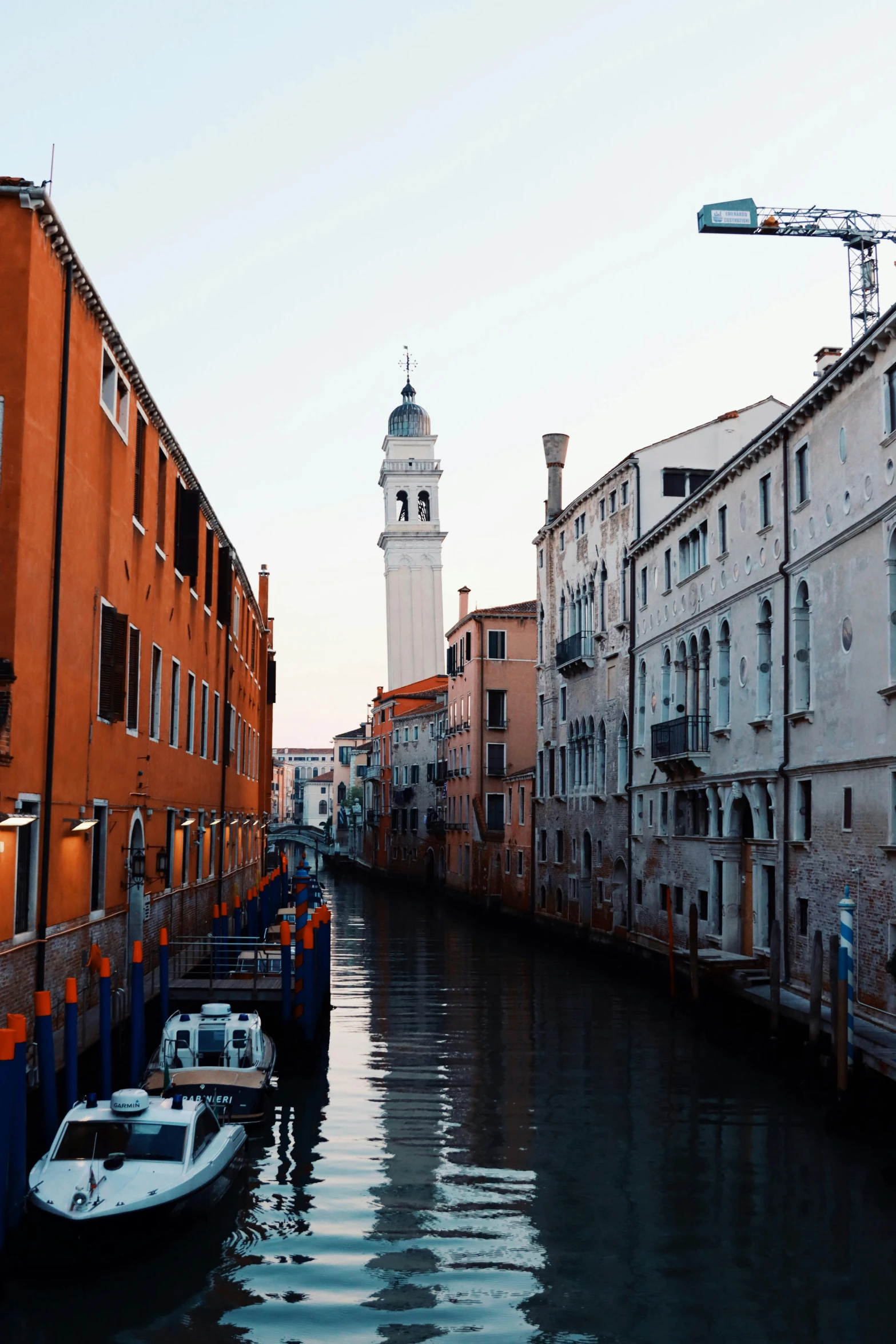 boats in the canal next to buildings and a clock tower