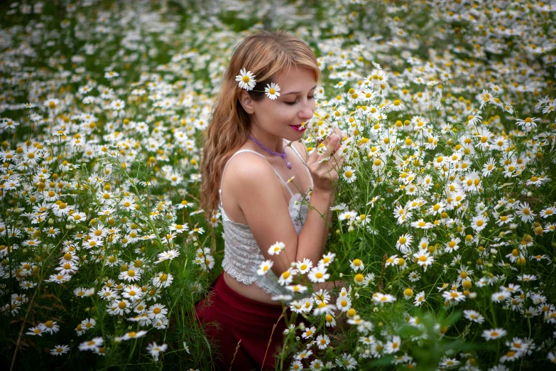 woman surrounded by daisies blowing on her nose