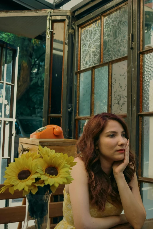 a woman sitting in front of a house with large sunflowers