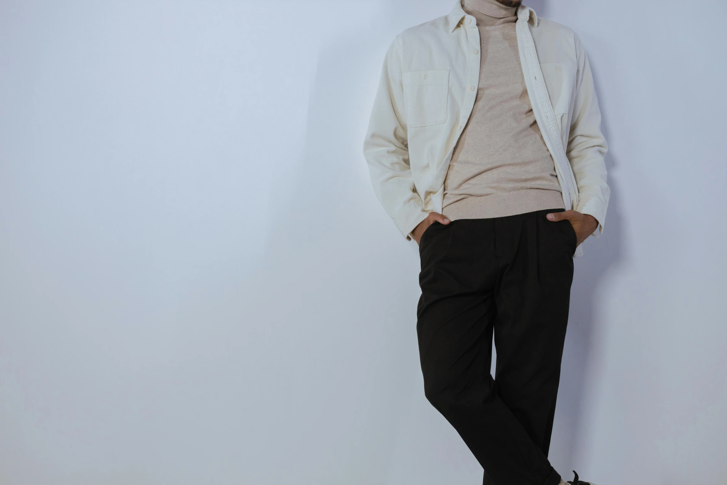 a young man standing in front of a white wall