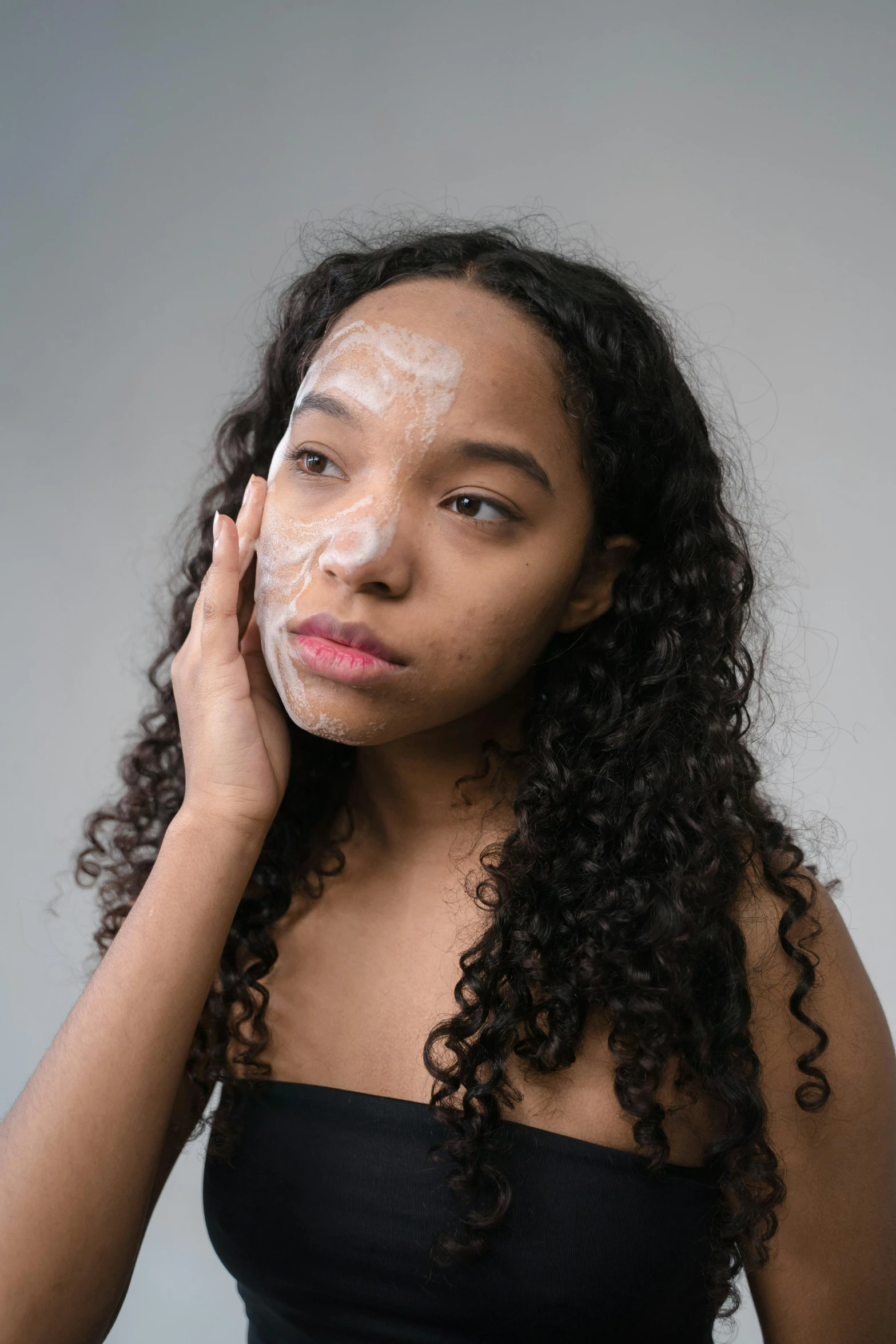 a woman holding her head to the side with a piece of cake on it