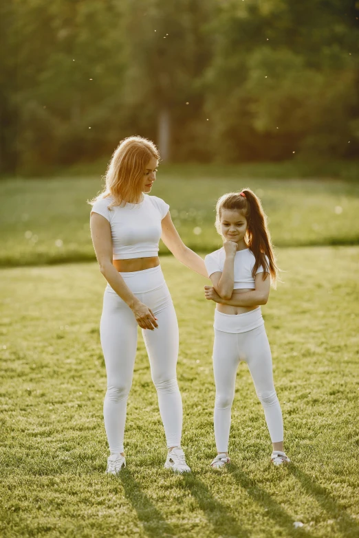 two women standing together while one in white is holding her hand up