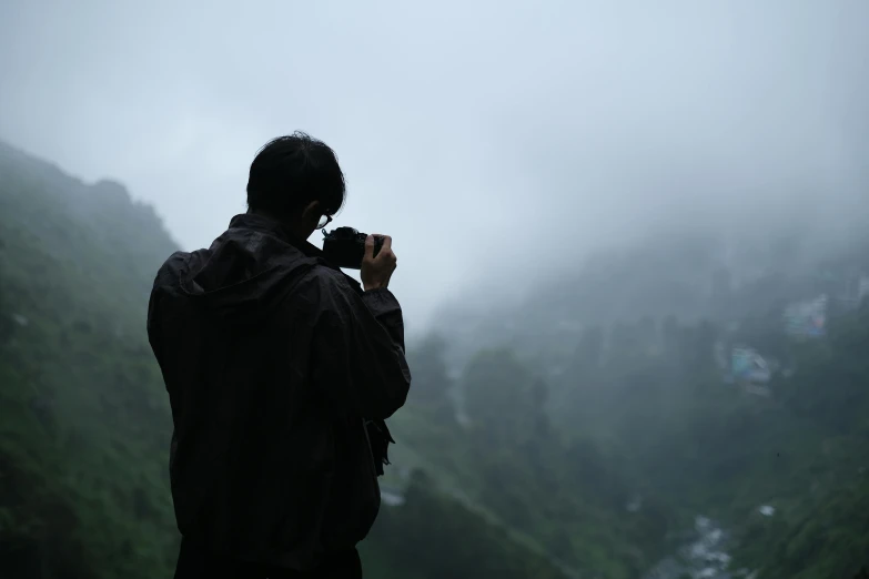 a man stands in front of a mountain with foggy mountains behind him