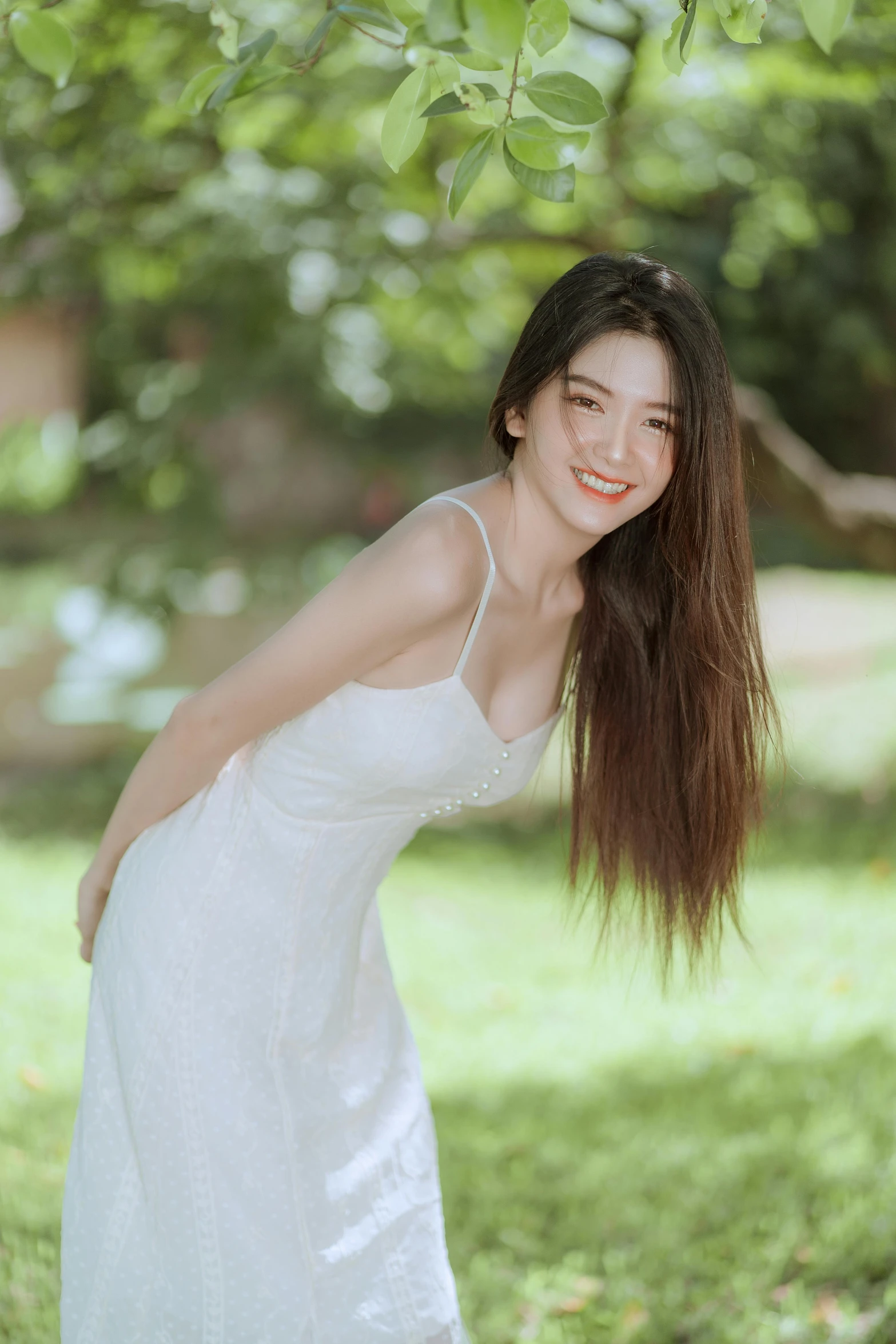 an asian woman in white is leaning against a tree