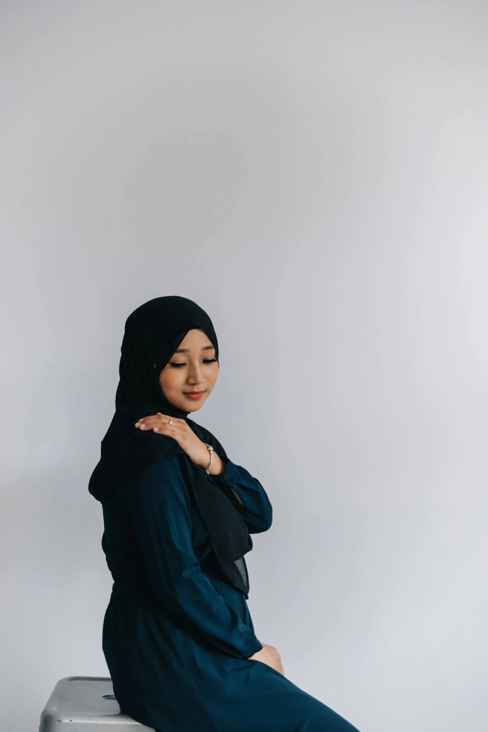 woman sitting on grey metal box posing for the camera