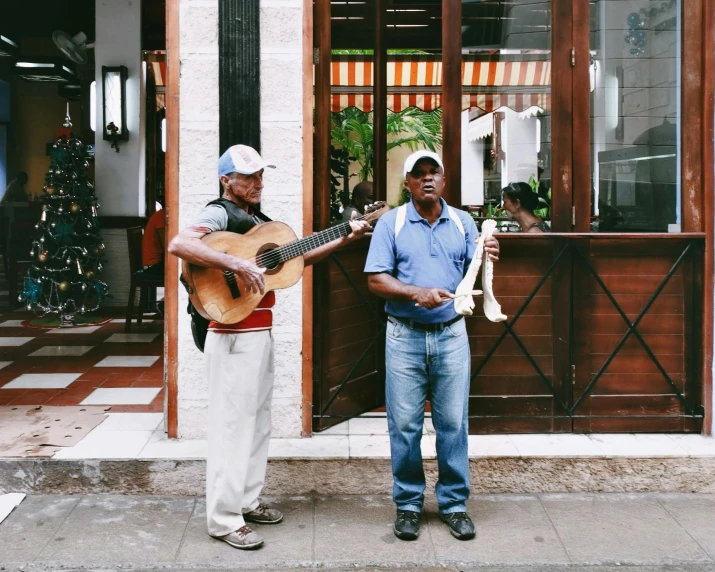 two men standing on the sidewalk holding guitars