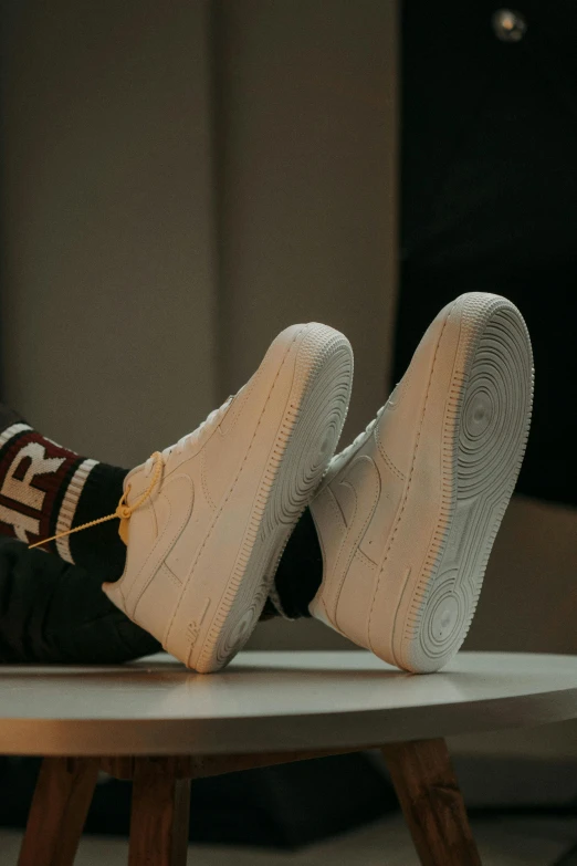 someone wearing socks and sneakers while sitting on a table