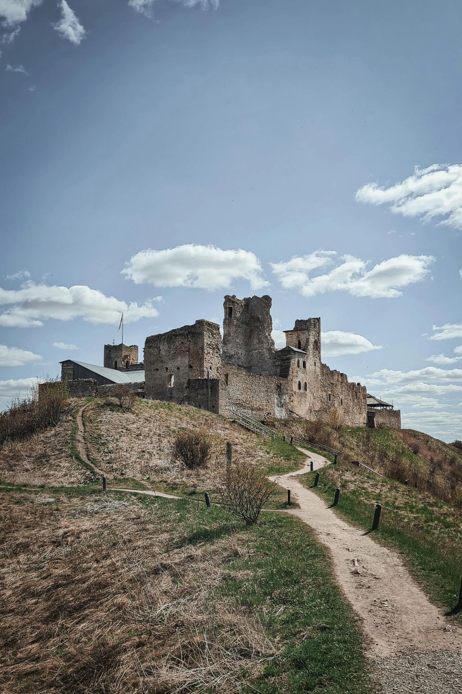 a small castle near a path under a partly cloudy blue sky