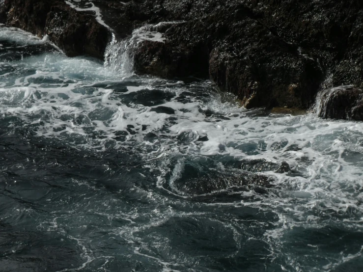 the rocks and water are next to the water