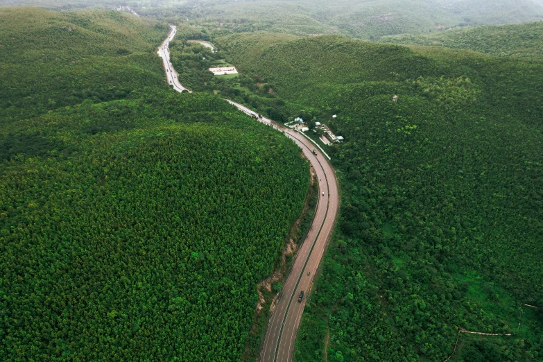 an aerial s of a rural road in the middle of green mountains