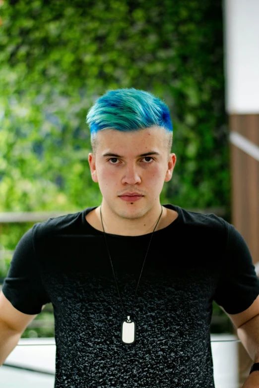 a young man with blue hair, wearing a black shirt and a necklace