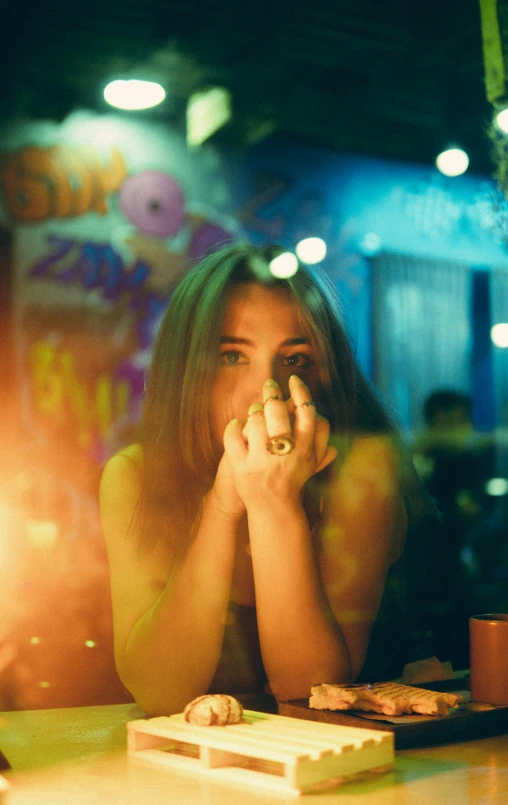 a woman in yellow sitting at a table with a phone