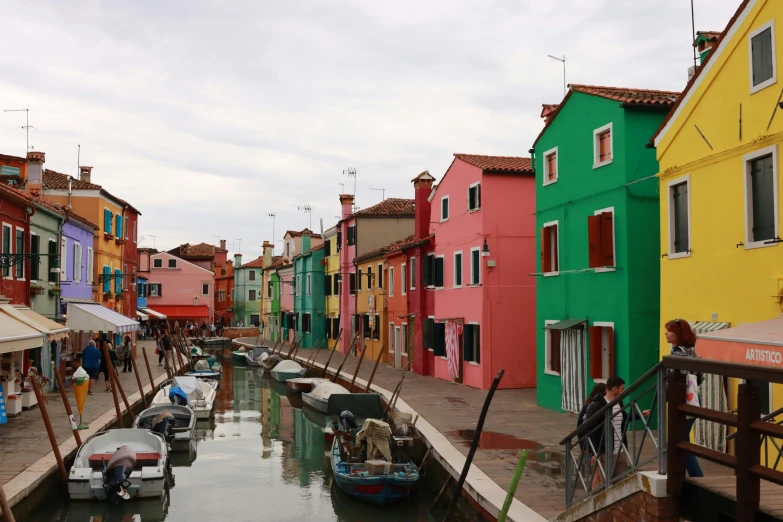 the narrow canal is lined with multi - colored buildings