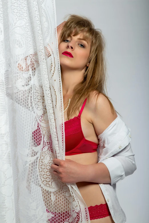 a beautiful woman standing next to a white curtain