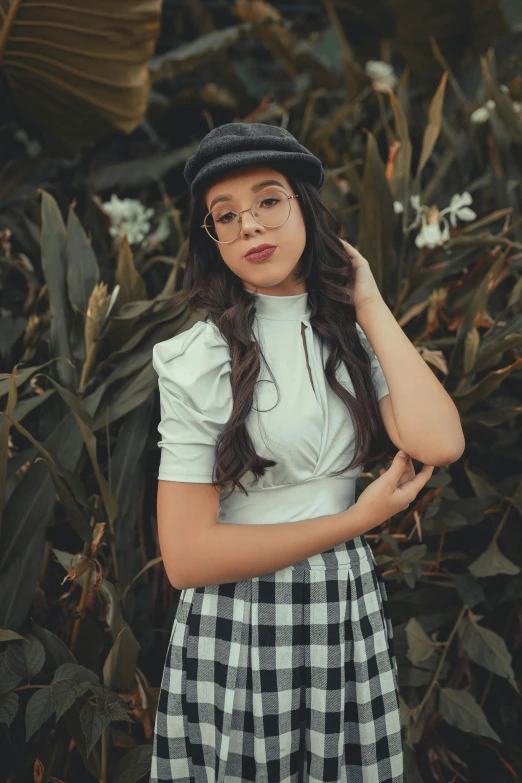 a young woman wearing glasses and a plaid dress poses for a portrait