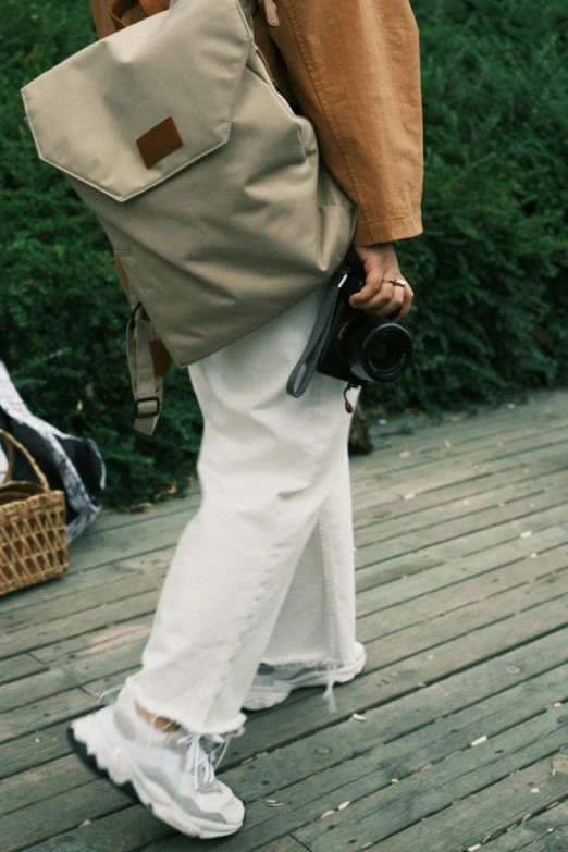 the back view of a person in a tan jacket with a brown and white backpack