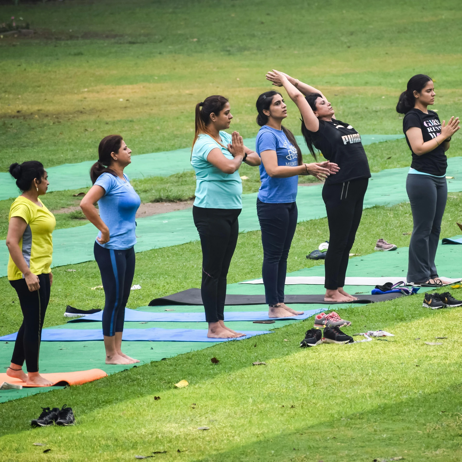 two woman standing on a yoga mat, in yoga poses and holding their hands up