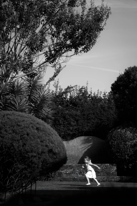 a woman is walking down the walkway in front of some trees