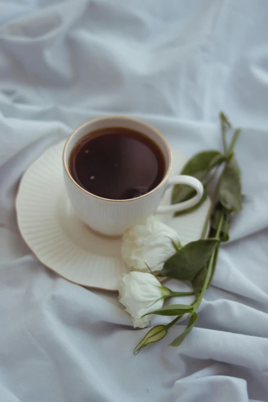 a white rose and coffee on a bed