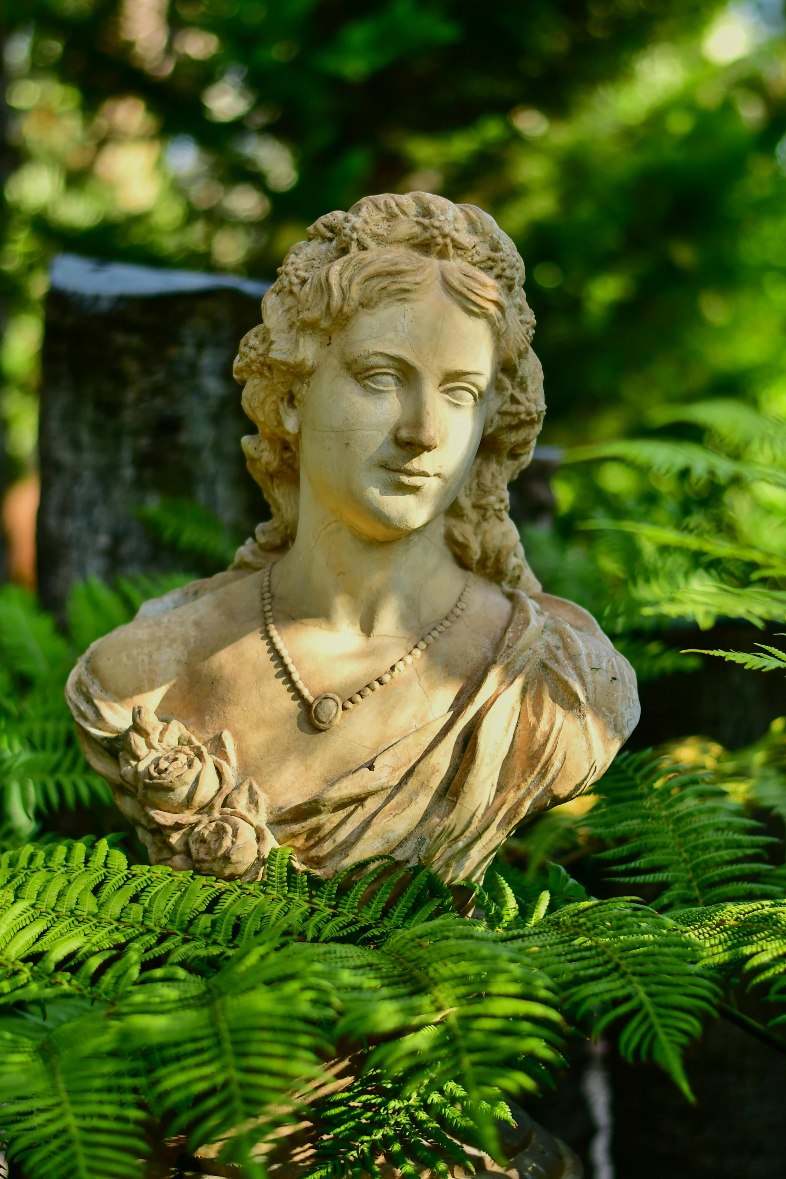 a sculpture of a girl in a forest of ferns