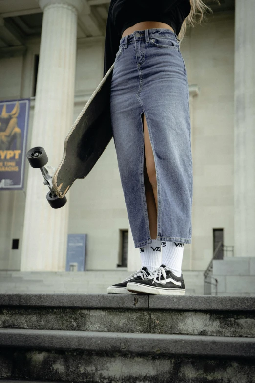 a person in jeans and sneakers holding a skateboard