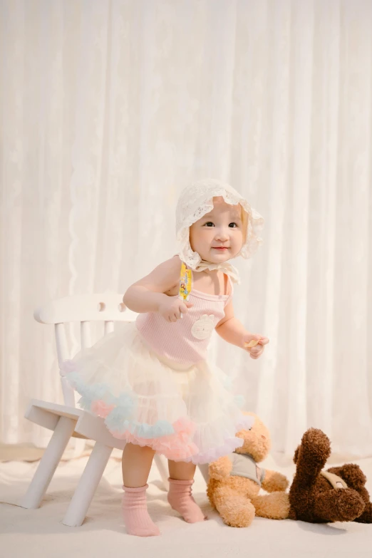 a baby in a dress sitting on a white chair