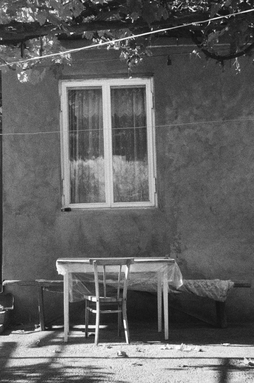 an empty chair is sitting at a table next to the window