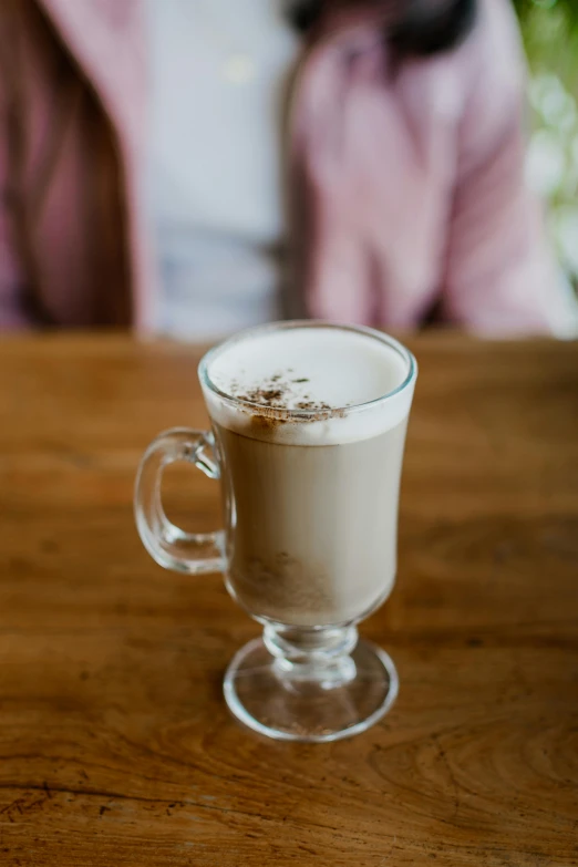 a woman sitting at a wooden table with a cup of coffee