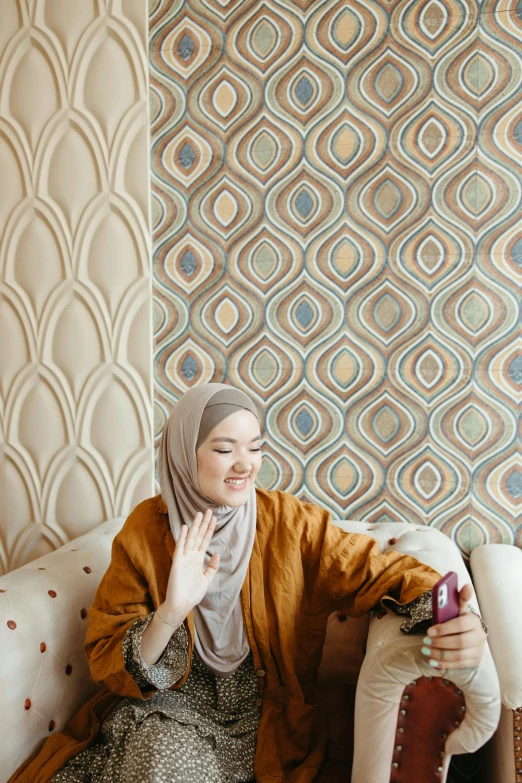 an islamic woman holding a cup on a couch