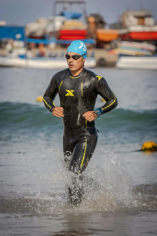 a man in wet suit running along side the ocean