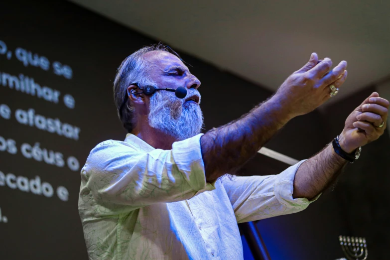 the man stands behind a microphone and holds his hand out