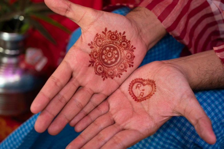 two hands holding small henders with red tattoo