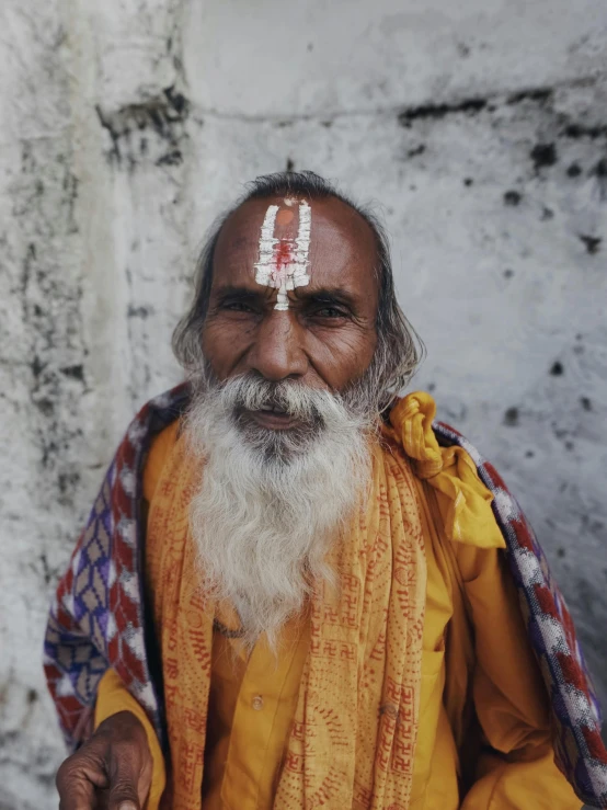 an old man is sitting in front of a wall