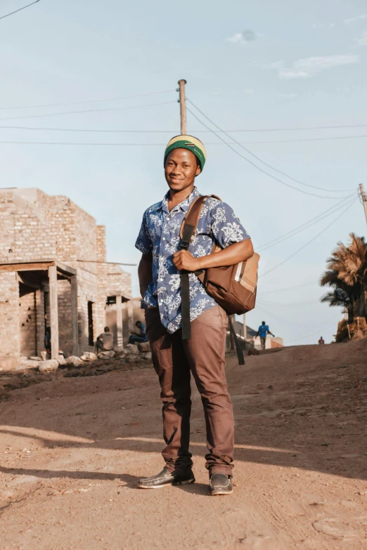 a man standing in the dirt while holding a brown bag