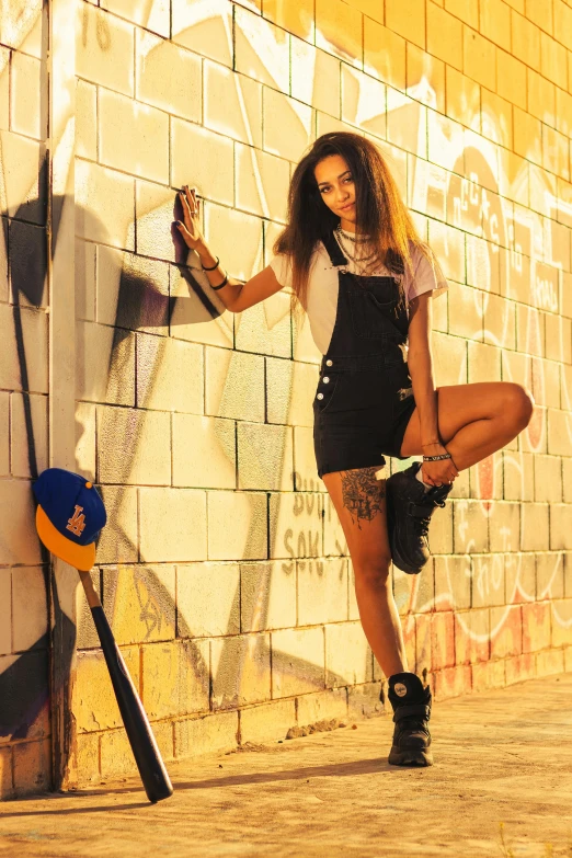 young woman leaning against a wall, holding a plastic bottle