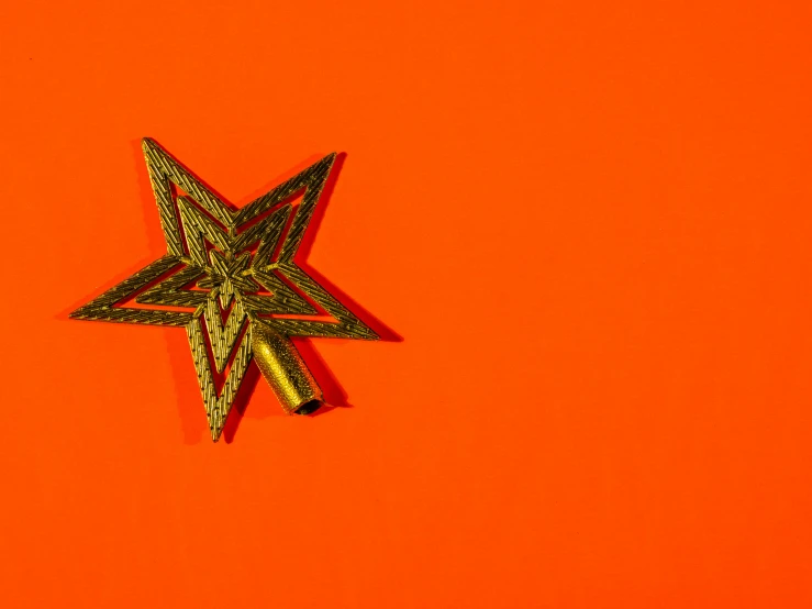 a gold star pins sitting on an orange surface