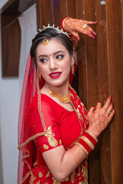 the woman is standing behind a wall wearing a red veil