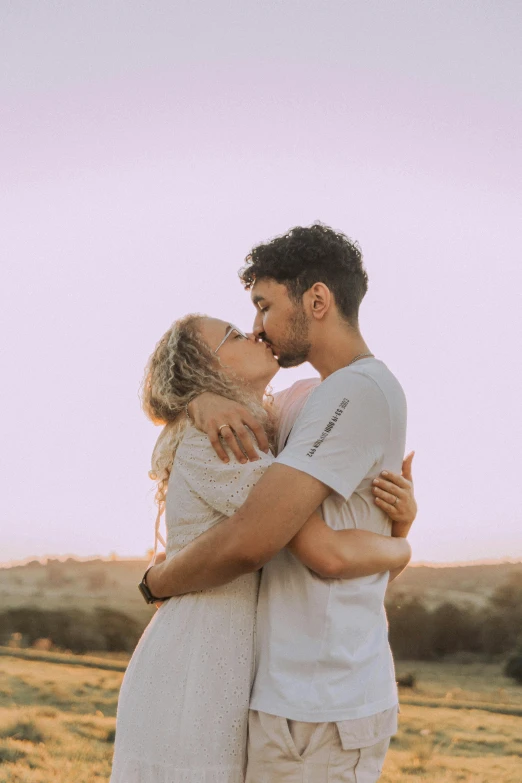 an engaged couple kissing in the countryside