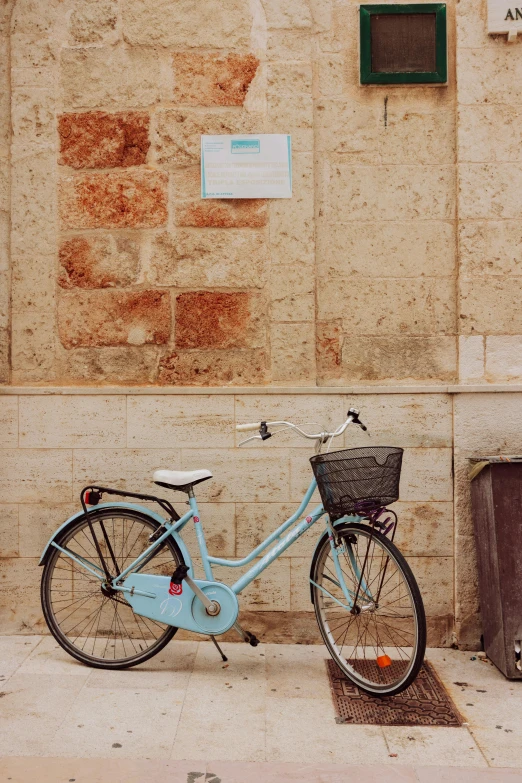 the bike is parked near a wall and a metal basket