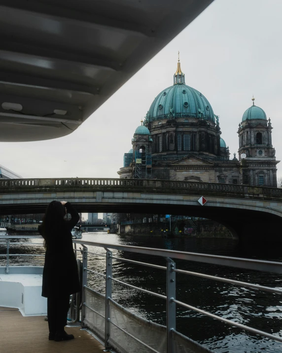 woman standing on pier with bridge and cityscape