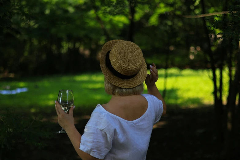 a lady is holding a wine glass up to her ear