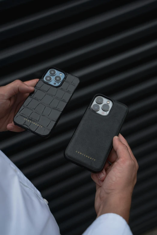 two persons holding cell phones and cases, one black