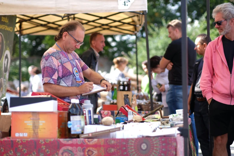 a man wearing eye glasses stands at an outdoor market