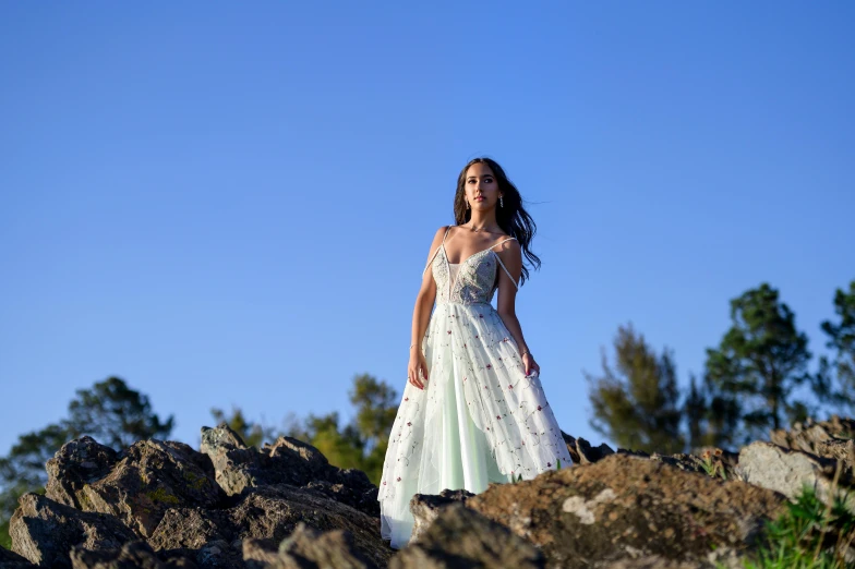 woman in white dress standing on large rocks
