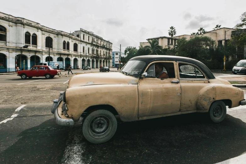 a large yellow car driving through a wet street