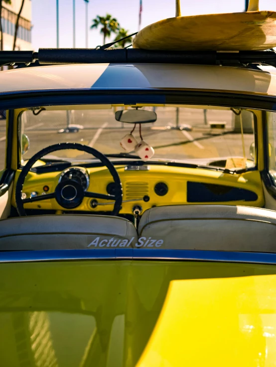 view from the drivers seat of a yellow car, with surfboards on top