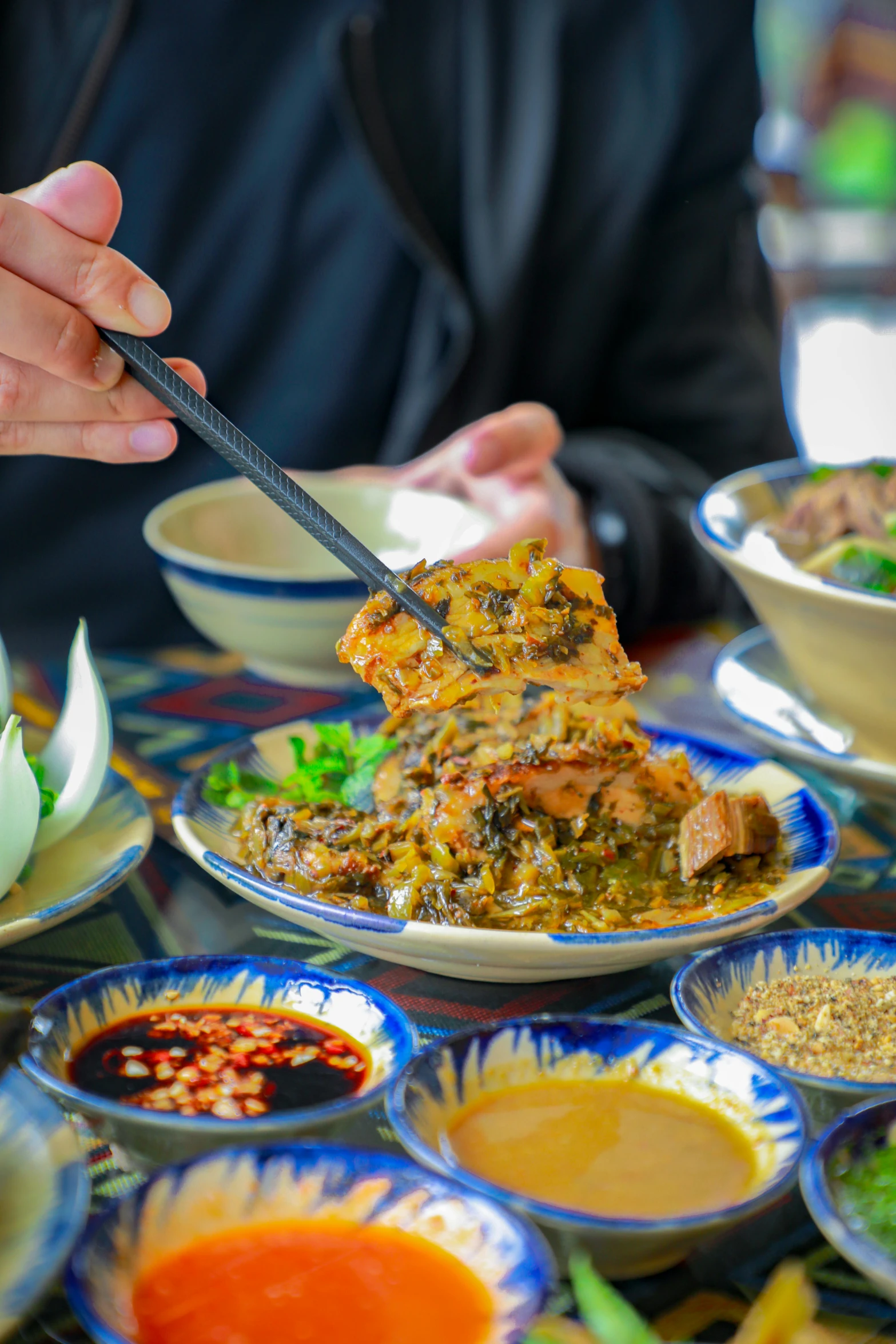 a person eating food on a table with many bowls of vegetables