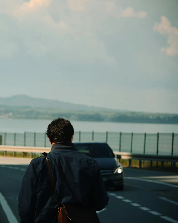 a man walks in front of cars down the road